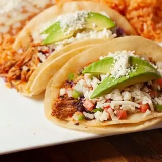 Tacos Reyes topped with avocado